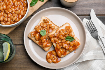 Toasts with delicious canned beans on wooden table, flat lay