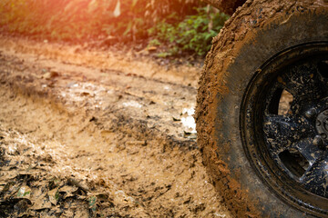 Fototapeta na wymiar Part of the muddy off-road wheels On a muddy road in the evergreen forest adventure concept forest tourism concept