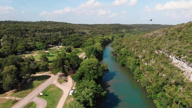 Aerial flyover idyllic Guadalupe River in Texas Hill Country surrounded by green landscape in summer