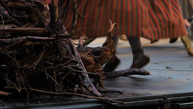 Adult dancers in traditional folk costumes perform in a dance performance in open air, Latvian national culture, medium shot of feet in simple footwear made of one piece of leather