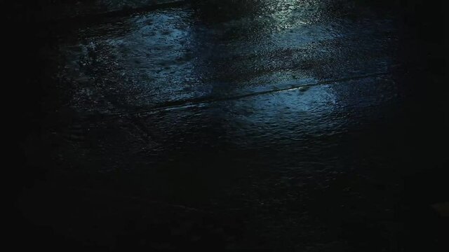 Blue light under the rain at late night on the street with little moving vehicles
