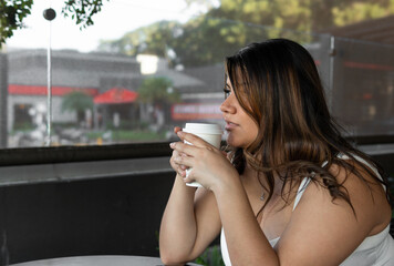 hispanic curvy girl drinking coffee  - obrazy, fototapety, plakaty