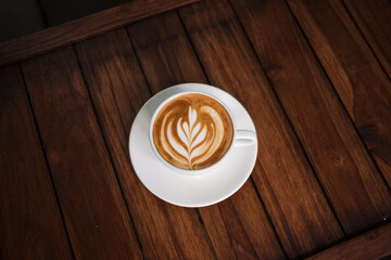 Latte art coffee on wooden table in coffee shop