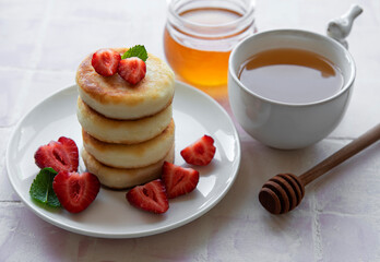 Cottage cheese pancakes, ricotta fritters on ceramic plate with  fresh strawberry.