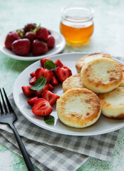 Cottage cheese pancakes, ricotta fritters on ceramic plate with  fresh strawberry.