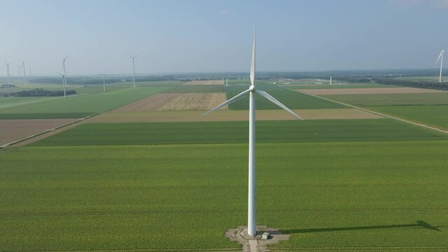Jib up of spinning wind turbine in a large windmill park in green meadows