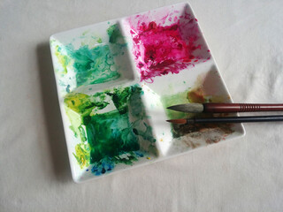white ceramic watercolor palette with colorful paints and brushes.