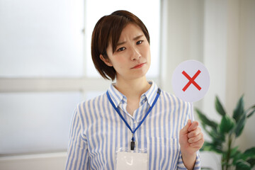 ×札を持つ女性社員