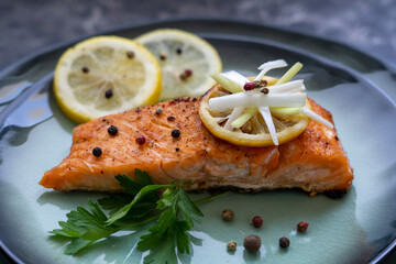 Side view of Salmon fish fillet cooked with different spices and served on plate.