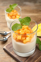 Delicious panna cotta with mango on wooden table