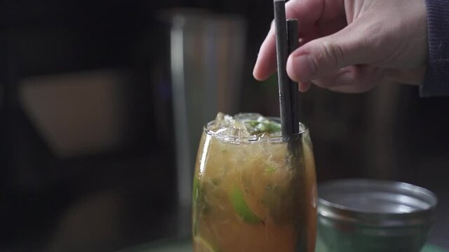 Slow motion shot of person putting straw in Tasty Cynar Drink,close up