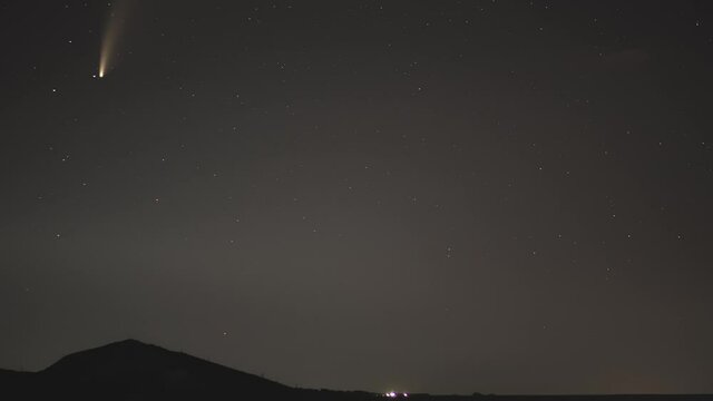 comet movement in the night sky among stars and meteors over the village in the mountains