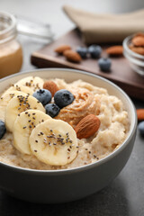 Tasty oatmeal porridge with toppings served on table, closeup