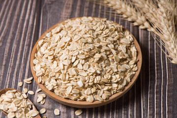 oat flakes or oatmeal in plate on wooden background