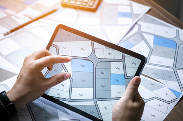 a man searching building plot on a cadastral plan to choose and buy a building plot for house construction on a digital tablet - obrazy, fototapety, plakaty