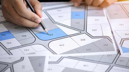 hand hold pencil to point on the cadastral map - choose and buy a building plot for house construction © Deemerwha studio
