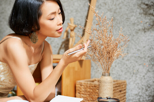 Beautiful creative young woman enjoying beauty of dred flowers in vase on coffee table
