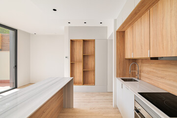 Modern kitchen interior with island and wooden furniture. Empty interior of bright refurbished apartment.