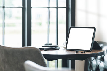 Blank screen tablet and gadget on wooden round table in cafe room.