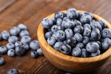 Freshly picked blueberries in wooden bowl on a wooden  table.