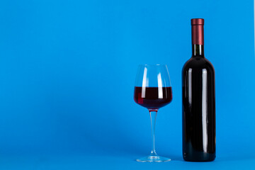 Wine bottle and glass on a blue background. Space for text. T
