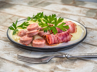 Breakfast with mashed potatoes, bacon and sausages, parsley sprigs, on a light table