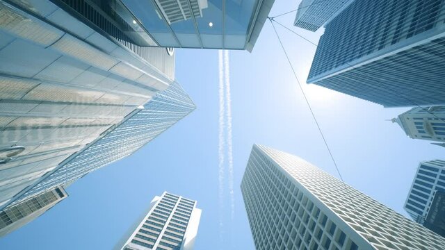 looking up view of city skyline buildings with aircraft.