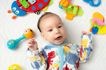 joyful baby lying on his back among toys