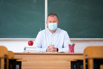 Teacher in the classroom wearing mask. Learning during coronavirus pandemic concept.