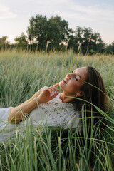 Dreamy and beautiful young woman relaxing in green field in summer  - 455220243