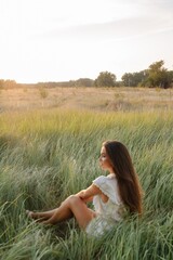 calm woman with long hair sitting in green field - 455220299