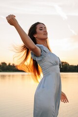 Model with long flying hair posing in sunset light near the river  - 455220627