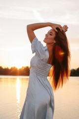 Fashion portrait of woman in beautiful dress posing at nature at sunset  - 455220640