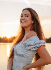 Beautiful smiling woman posing at sunset outdoors and looking at camera  - 455220684