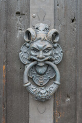 scary door knocker as a devil on an old wooden door