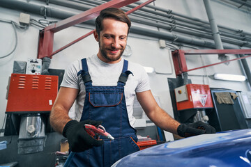 Satisfied mechanic using air gun for cleaning car part surface