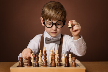 Little Kid playing Chess Game. Intelligent Small Boy in Eyeglasses next to Chessboard. Child...