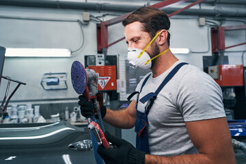 Happy technician holding sander and air blow gun in hands - obrazy, fototapety, plakaty