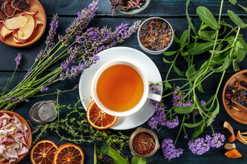 Obraz na płótnie Canvas Tea. Herbs, flowers and fruit around a cup of tea, an overhead flat lay shot on a dark rustic wooden background