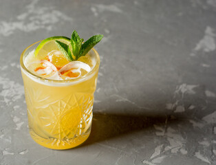 Fresh Mojito cocktail with lime, rosemary, mint and ice in jar glass on dark concrete background. Studio shot of drink in freeze motion, drops in liquid splash. Summer cold drink and cocktail