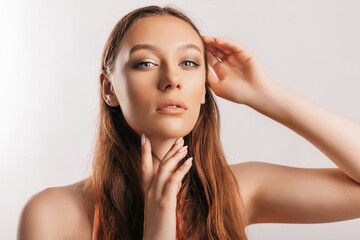 Fototapeta premium Beautiful young girl smiling and posing looking at the camera on a white isolated background with mockup. Positive brunette woman. Kind look. Beauty face