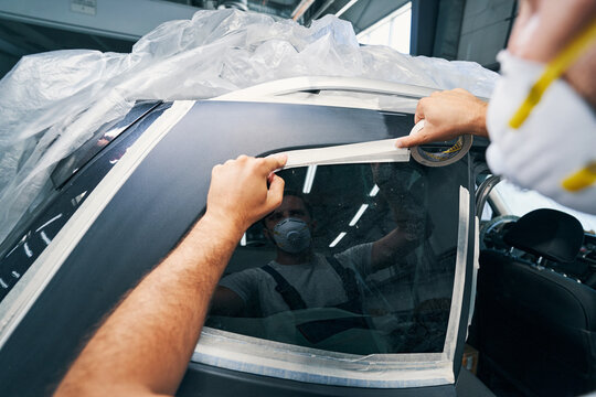Car service technician sticking duct tape on window