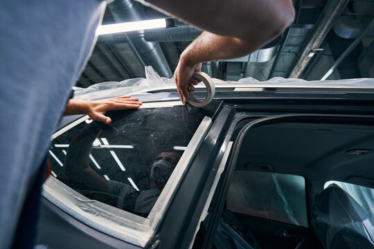 Repairman isolating windows of car with insulating tape
