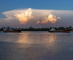 Bangkok, Thailand - 19 Apr 2020 : Two cargo ships parked in the middle of the Chao Phraya River and Dramatic sky background  in the evening.