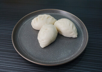 Chinese Hong Kong steamed fresh yellow corn custard bun vegan white bao zi in leaf shape on dark grey wood table asian dim sum halal food restaurant cuisine banquet menu for cafe