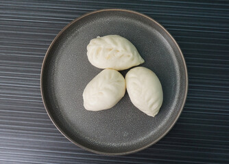 steamed fresh yellow corn custard bun white baozi in leaf shape on dark grey wood background dim...
