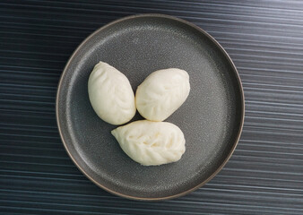 steamed fresh yellow corn custard bun white baozi in leaf shape on dark grey wood background dim sum halal menu