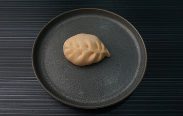 steamed fresh curry potato vegan bun orange baozi in leaf shape on dark grey wood background dim...