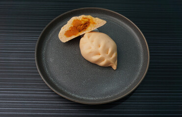 steamed fresh curry potato vegan bun orange baozi in leaf shape on dark grey wood background dim sum halal menu