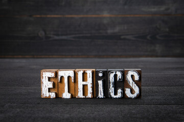 ETHICS. Business, attitudes and education concept. White wooden letters on a dark wooden background